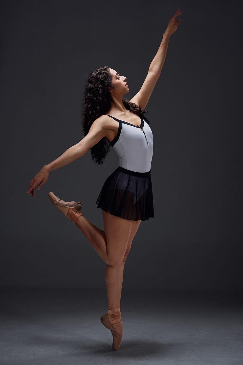 Bailarina en tutú blanco posando elegantemente en el escenario